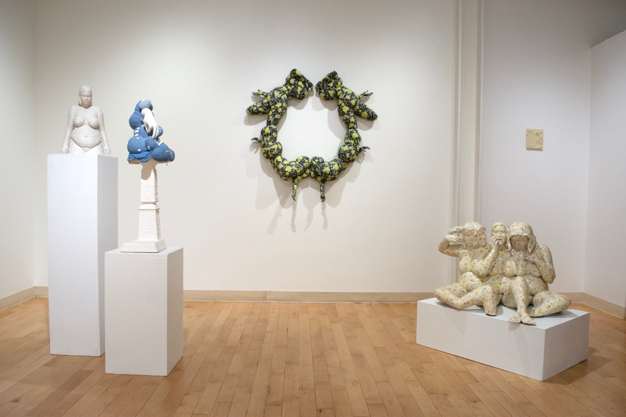 A gallery hosts sculptures on pedestals and hung on walls.